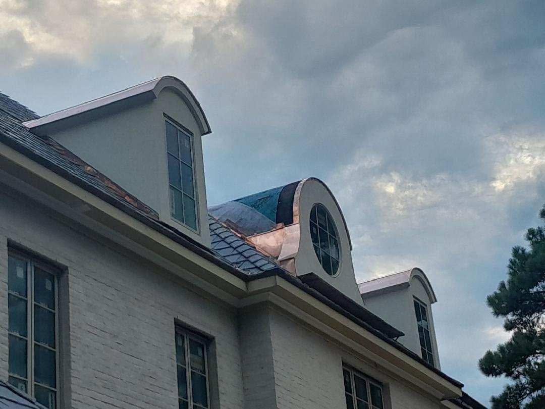 Copper-roofed dormers and gray roof courses in a Maddox specialty project